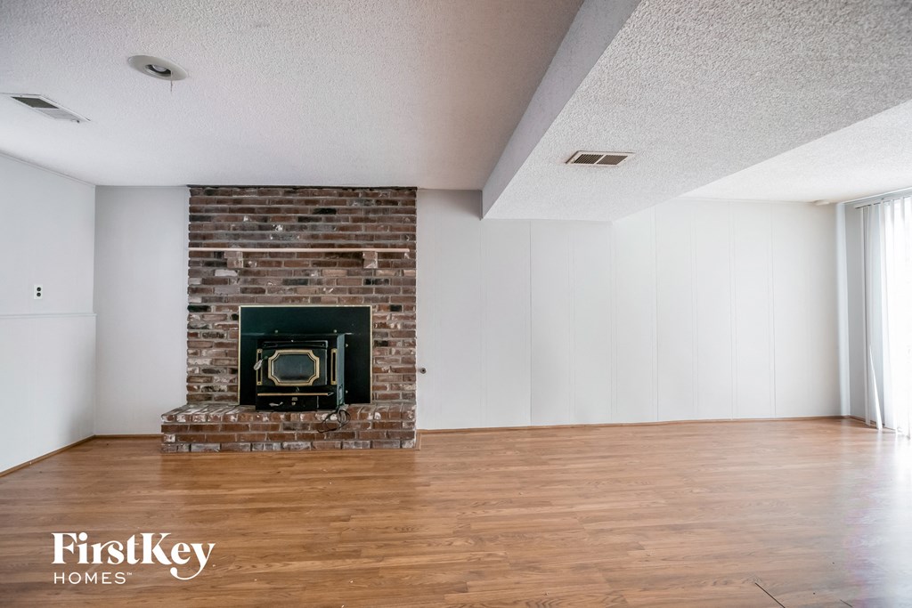 the living room with wood flooring and a brick fireplace