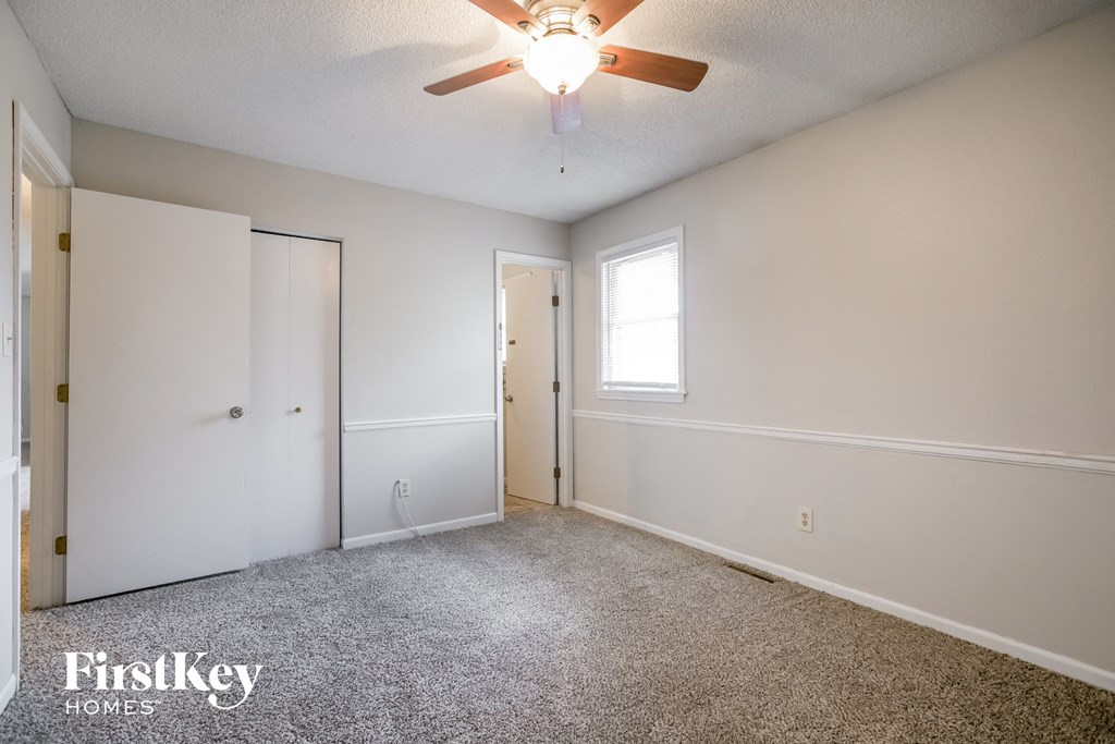 a bedroom with white walls and a ceiling fan