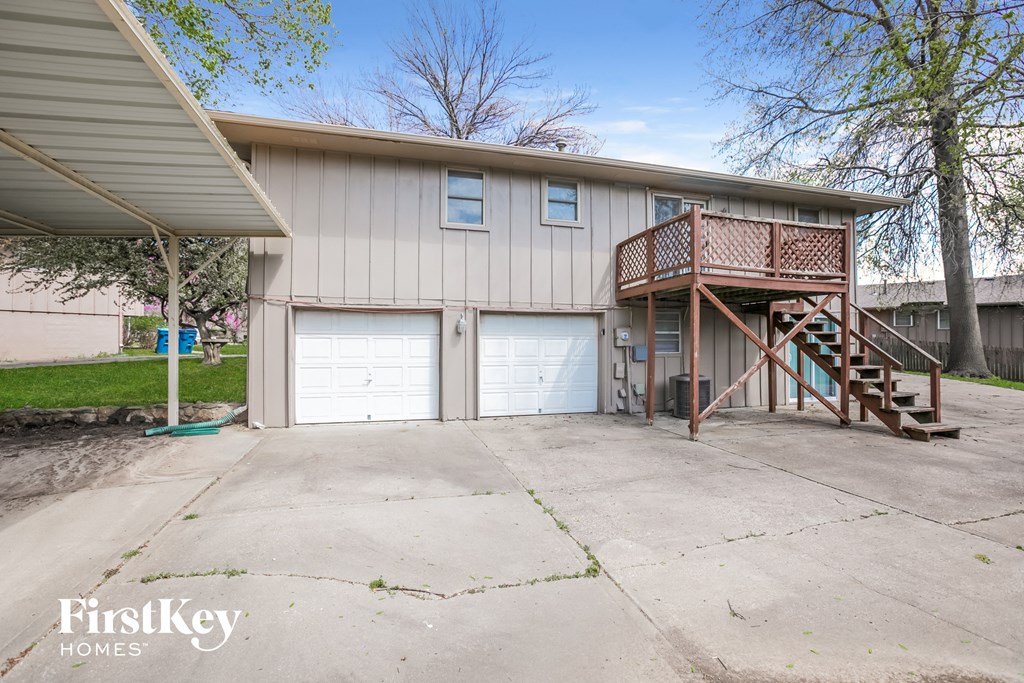 a white house with two garage doors and a staircase