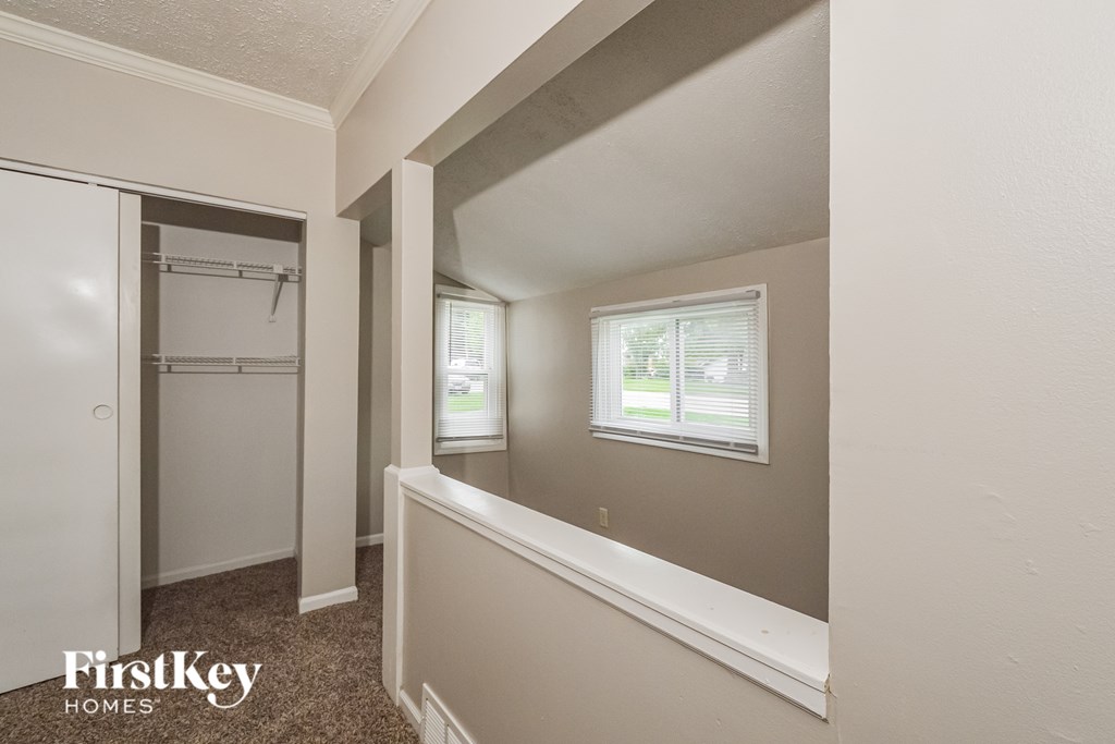 A small bedroom with a window and a closet.