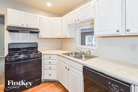 A kitchen with a black stove top oven and a black dishwasher.