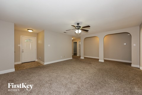 A spacious room with a ceiling fan and carpeted floor.