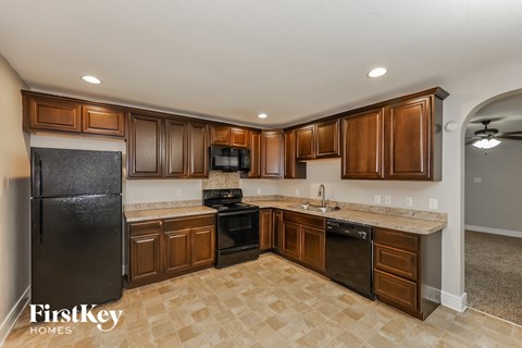 A kitchen with brown cabinets and a black refrigerator.