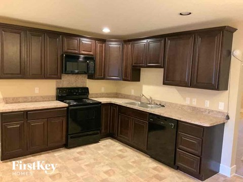 A kitchen with dark brown cabinets and a black stove top oven.