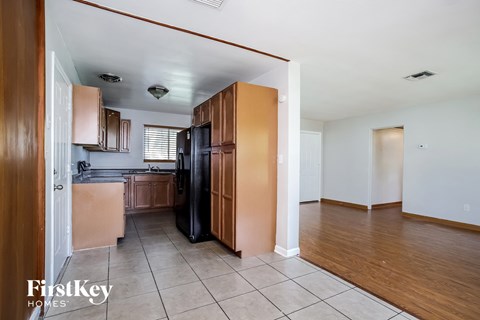 A kitchen with wooden cabinets and a black fridge is shown.