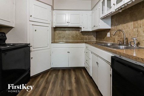 a kitchen with white cabinets and a sink and a stove