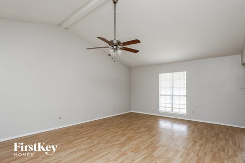 A room with a ceiling fan and wooden flooring.