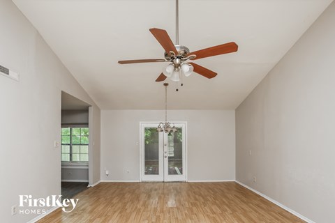 A room with a ceiling fan and a door leading to another room.
