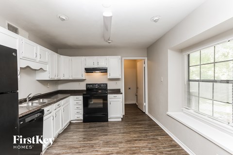 A kitchen with white cabinets and a black stove top oven.