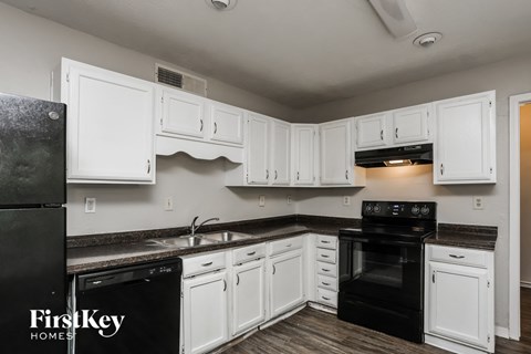 A kitchen with white cabinets and black appliances.