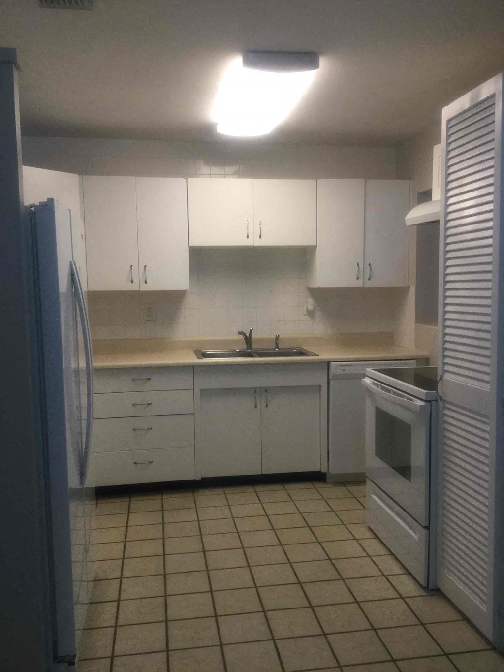 a kitchen with white cabinets and a sink and a refrigerator