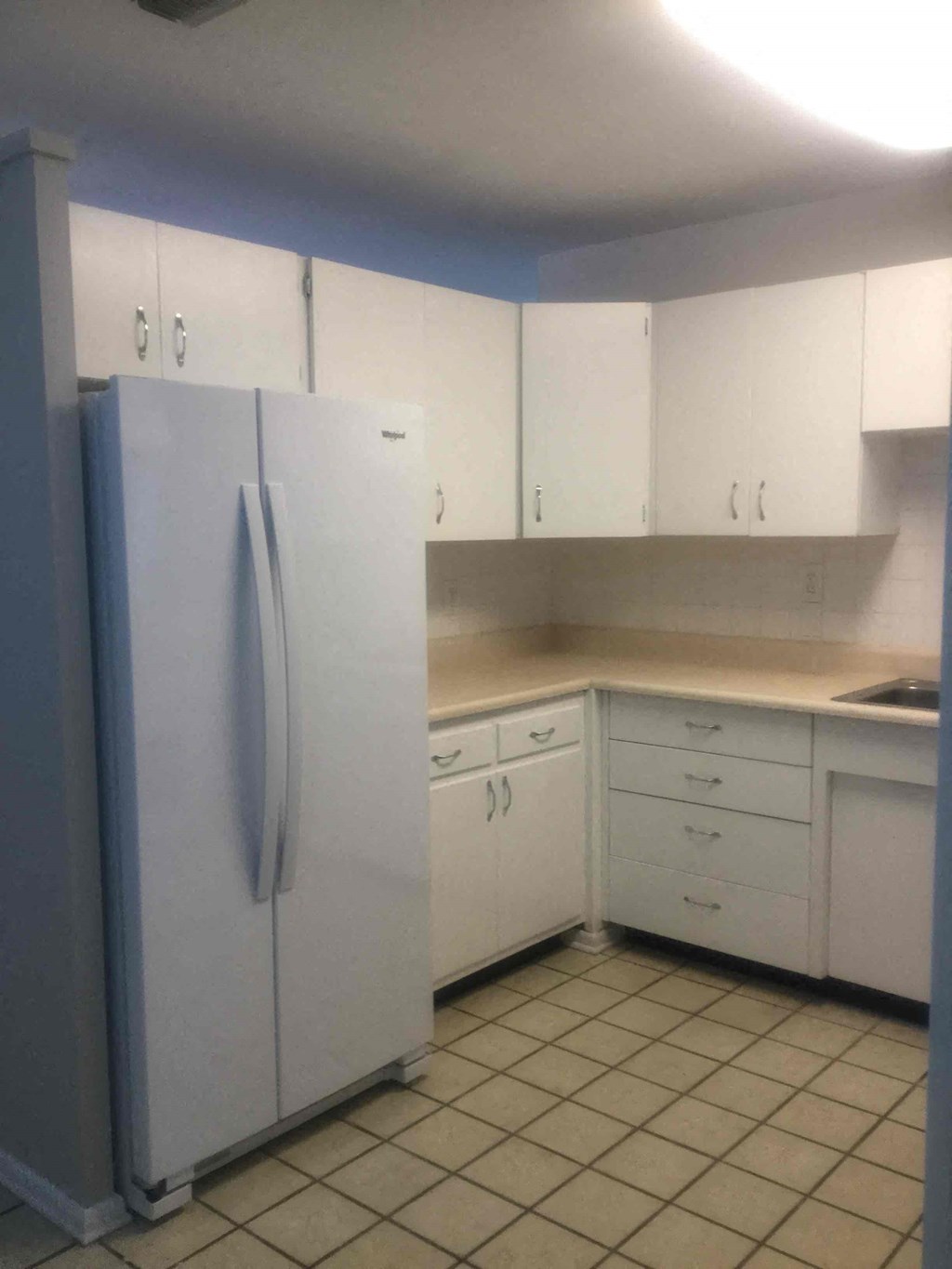 a kitchen with white cabinets and a refrigerator