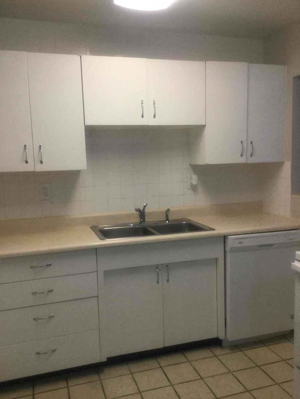an empty kitchen with white cabinets and a sink