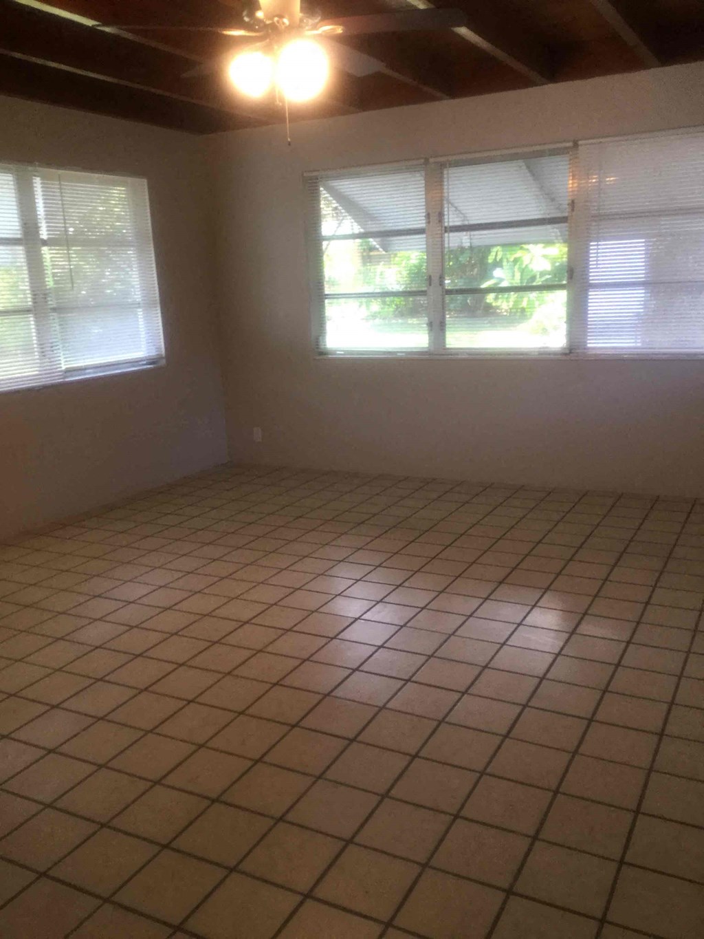 an empty room with a tiled floor and three windows