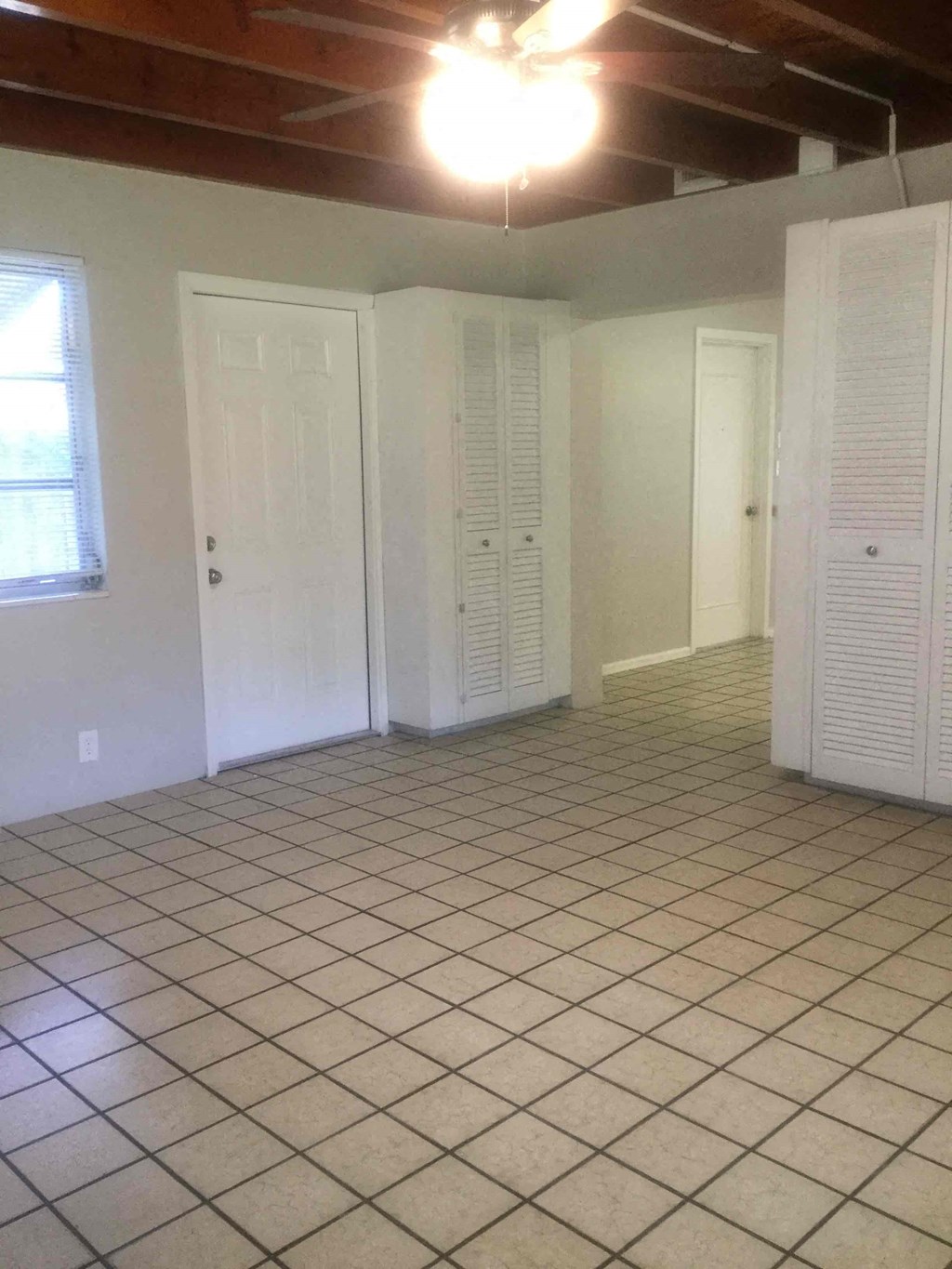 an empty living room with a tile floor and white doors