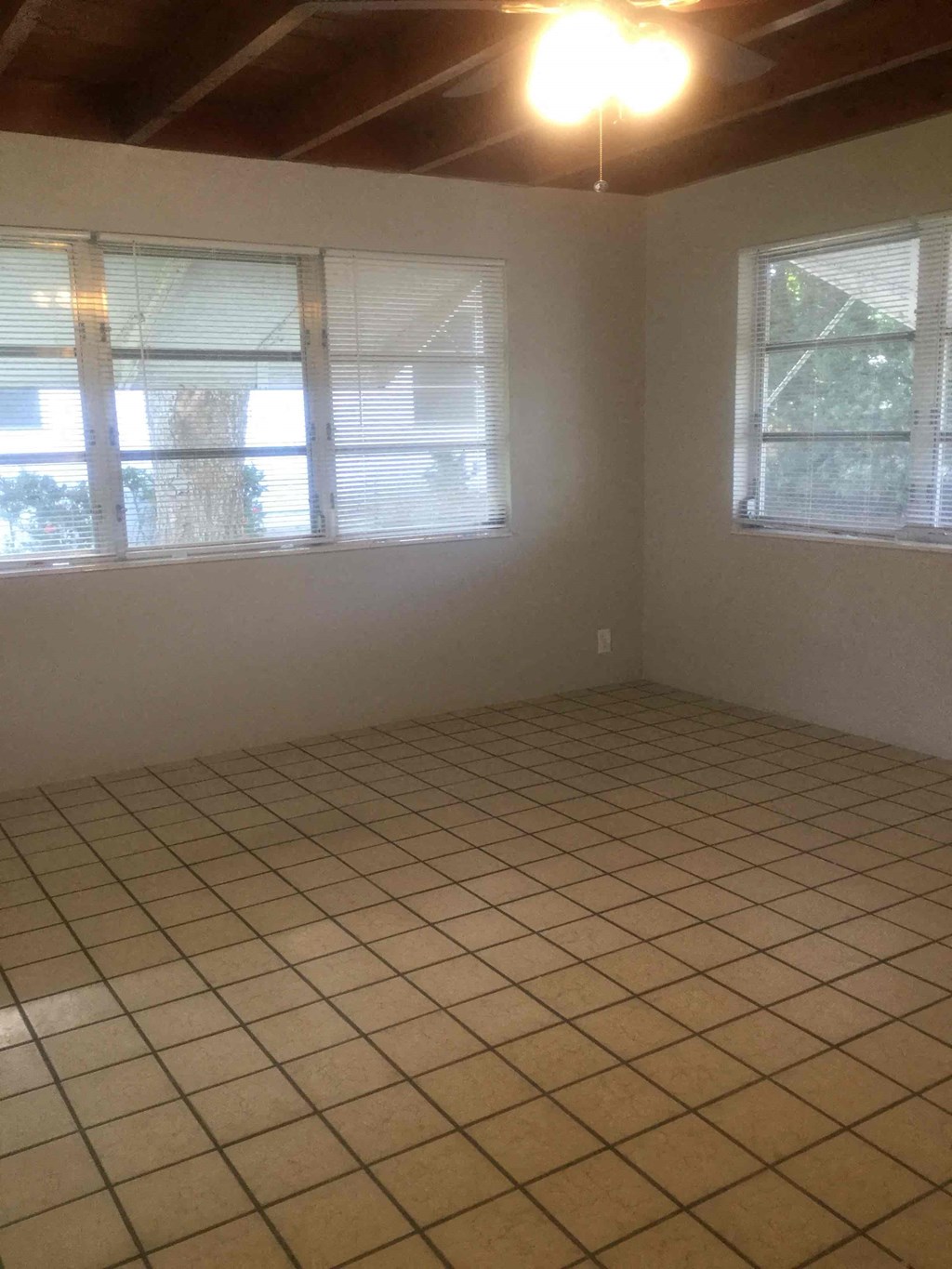 an empty room with a tiled floor and three windows