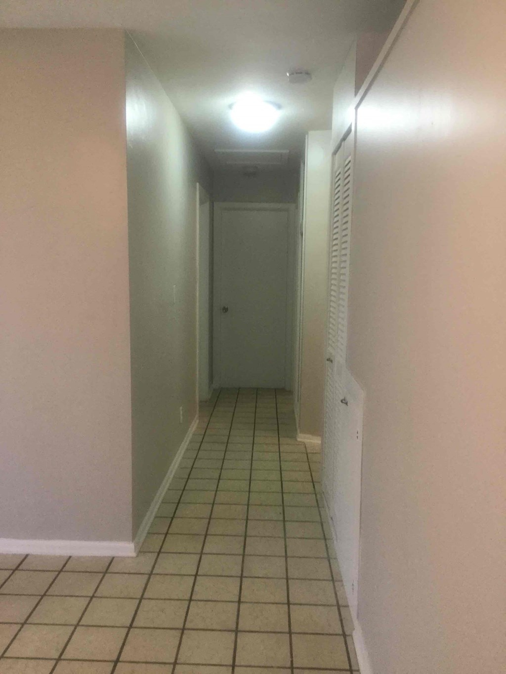 a hallway with a tiled floor and a white door
