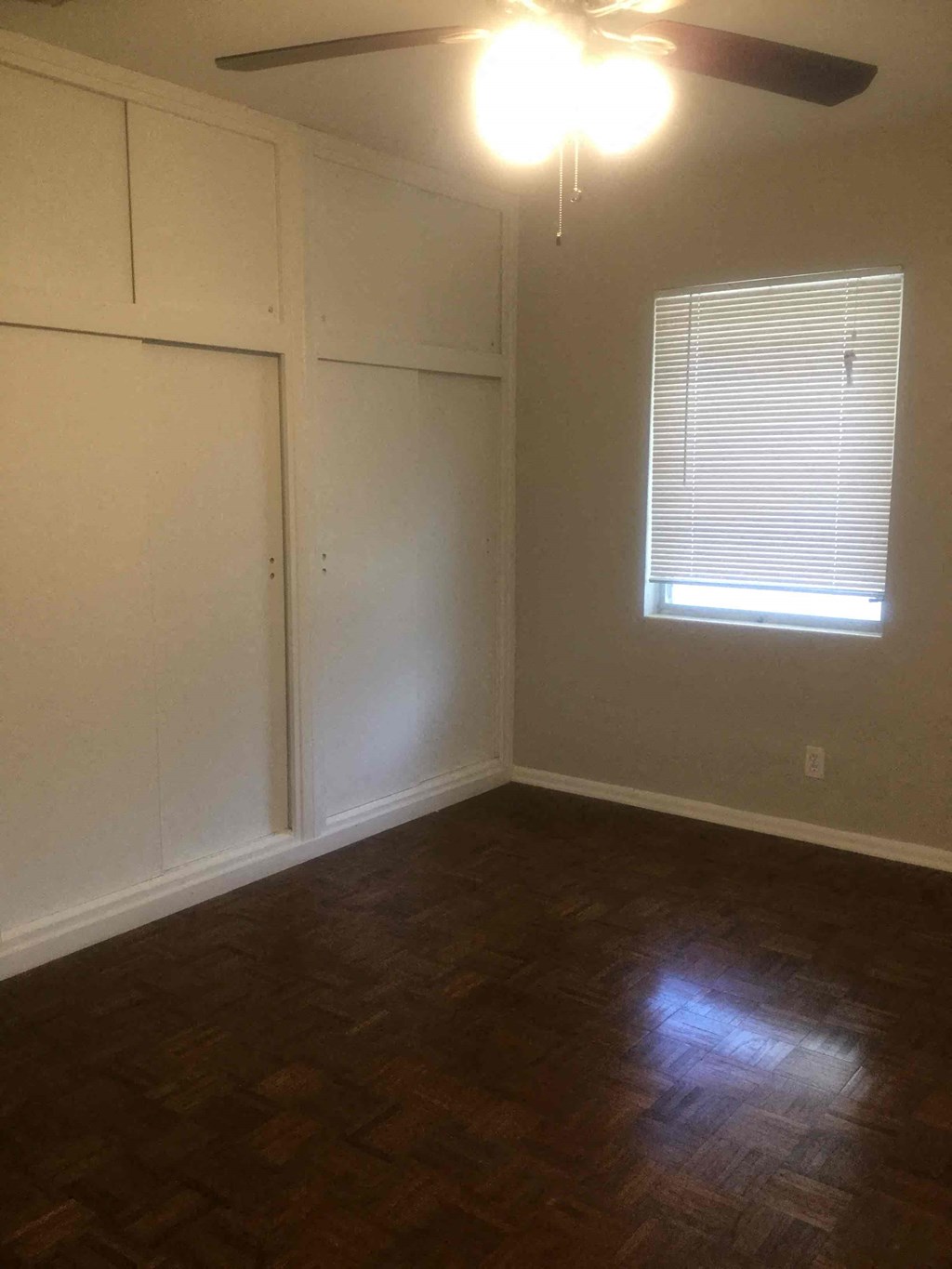 an empty room with a ceiling fan and a window