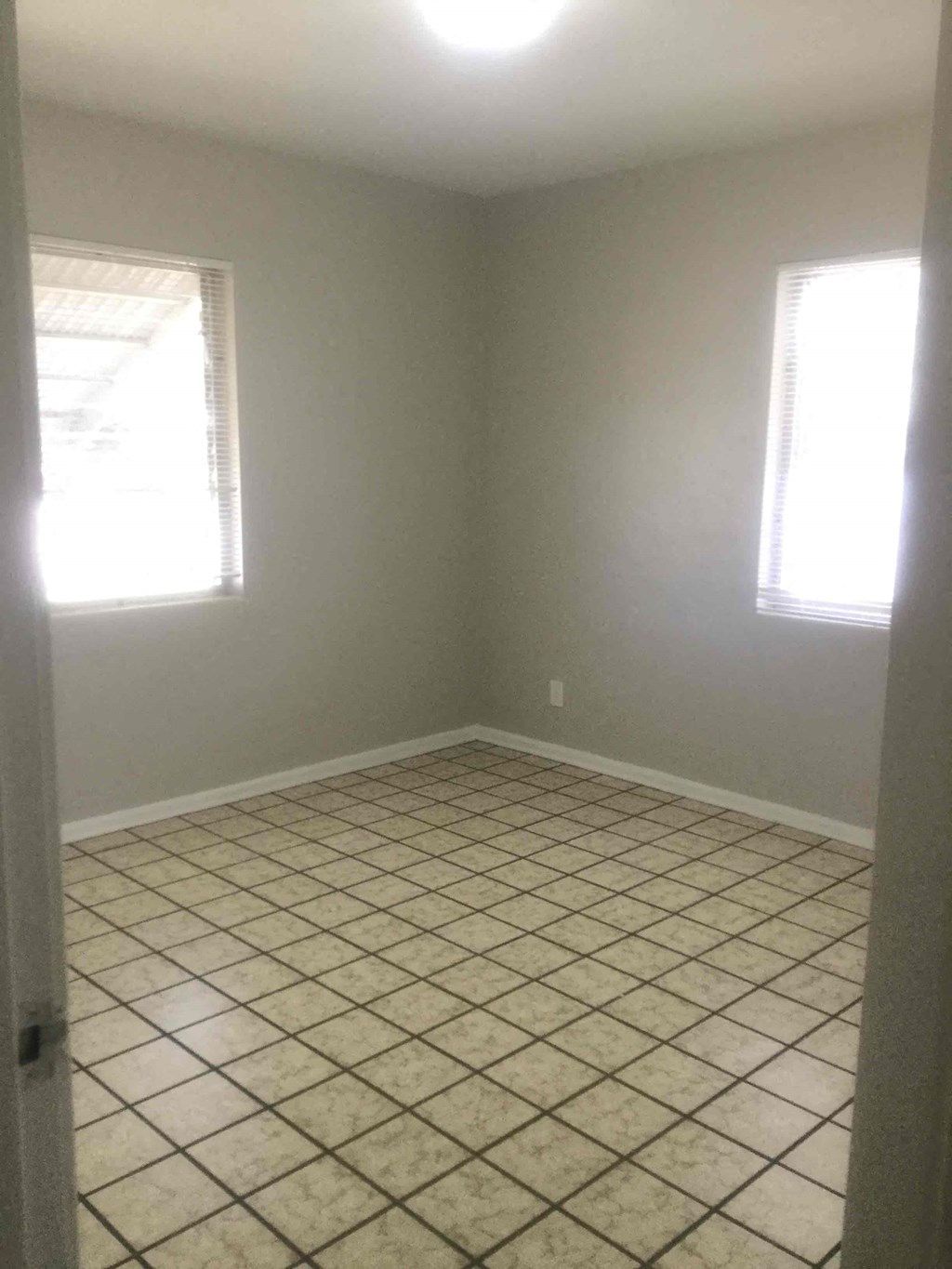 an empty room with a tiled floor and two windows