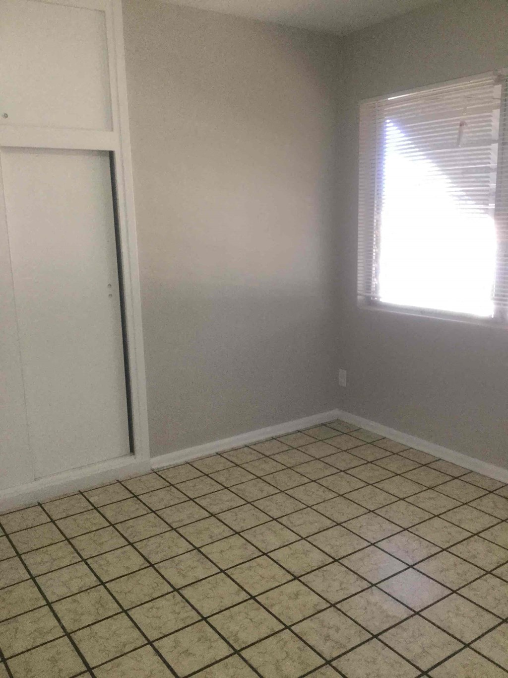 an empty room with a tiled floor and a closet