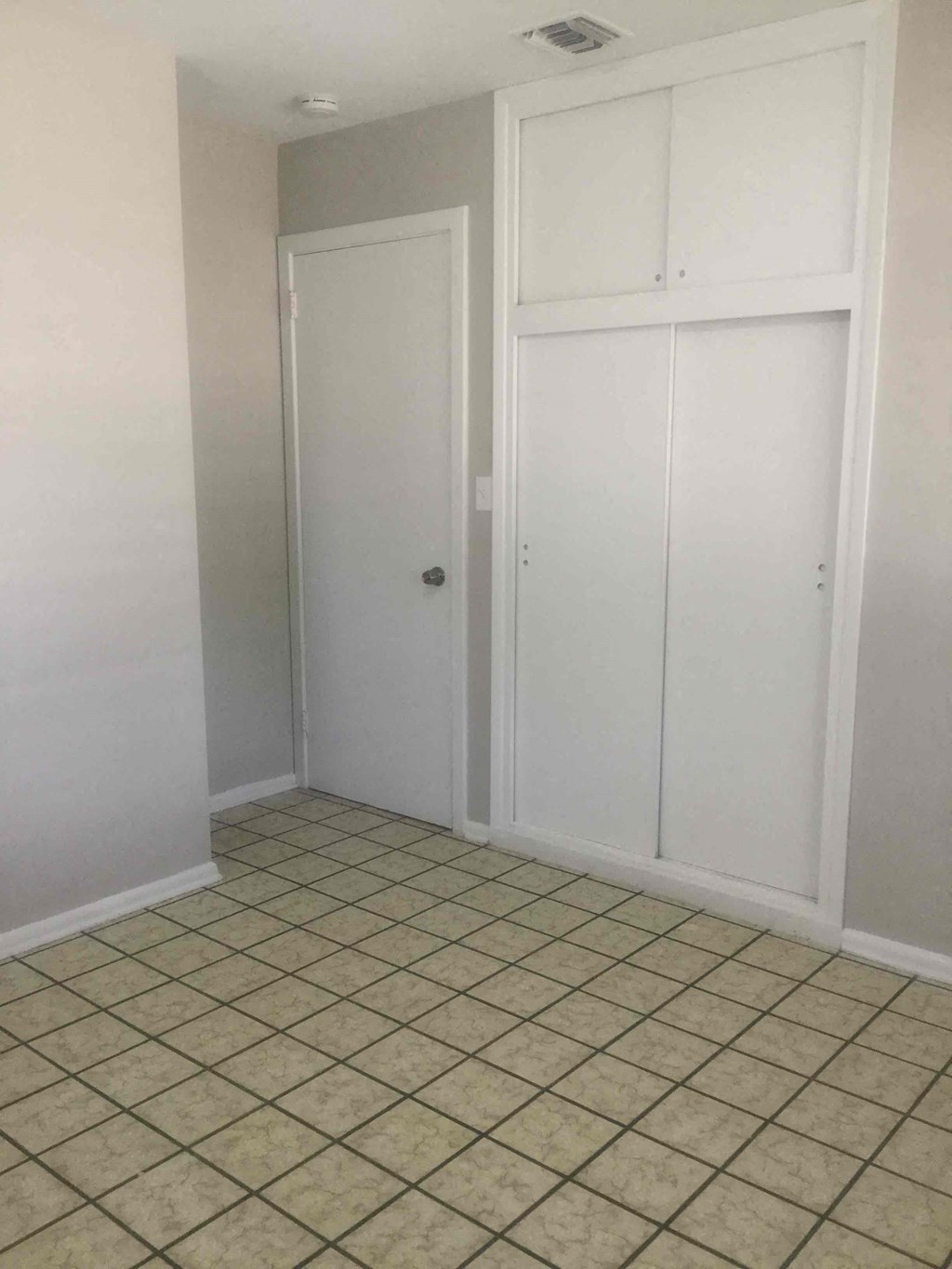 an empty room with two closet doors and a tiled floor