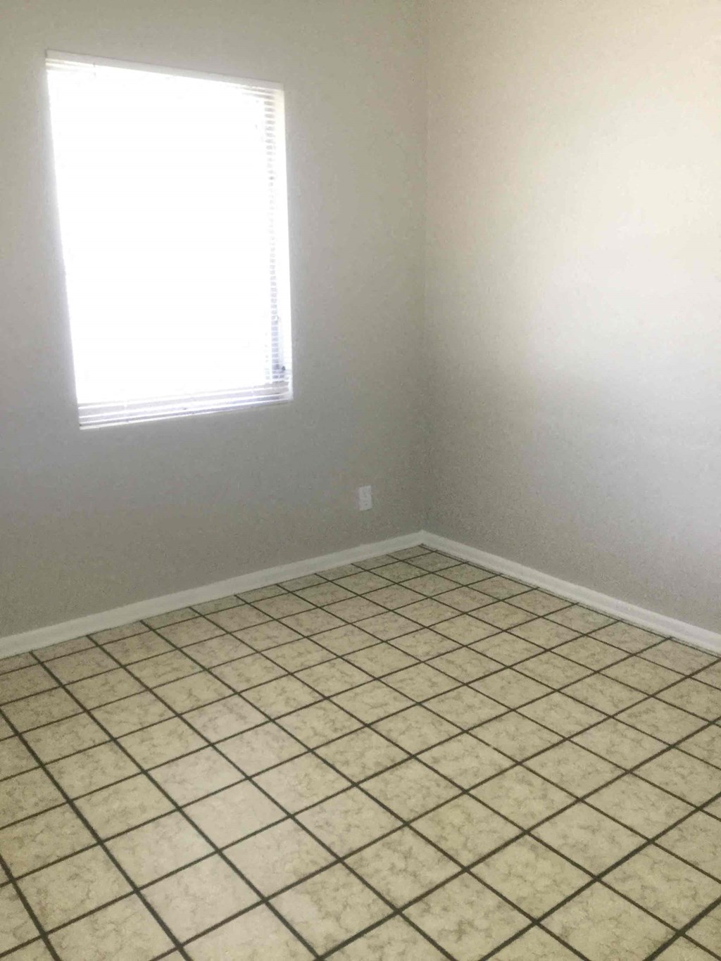 an empty room with a window and a tiled floor
