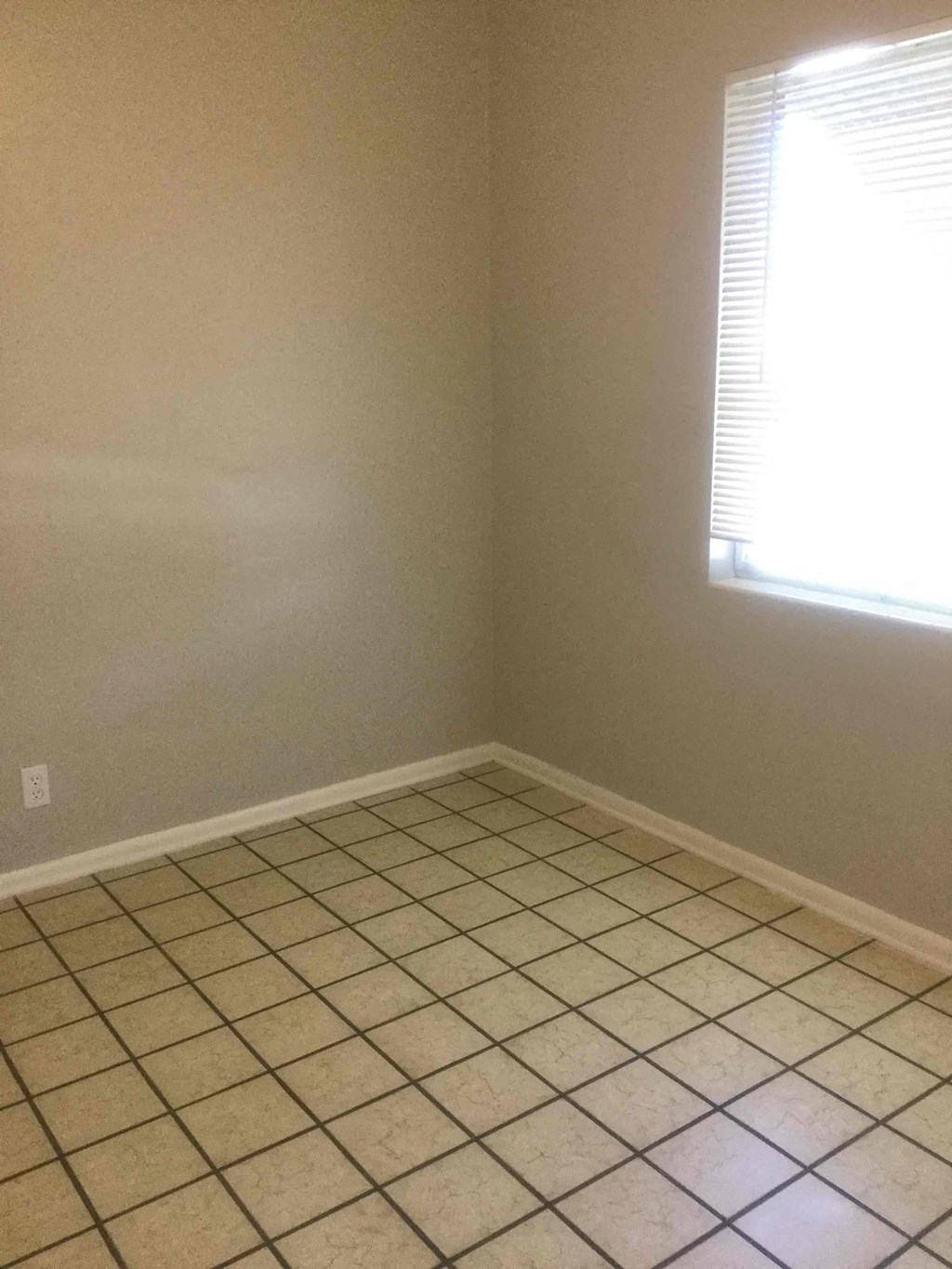 an empty room with a tiled floor and a window