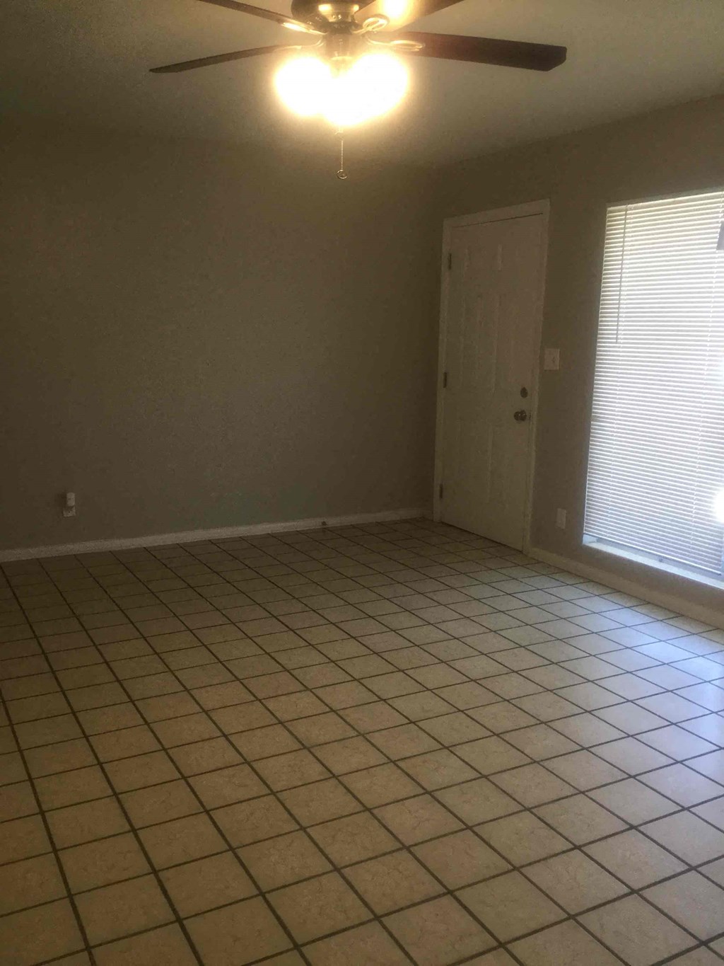 an empty living room with a ceiling fan and a tiled floor