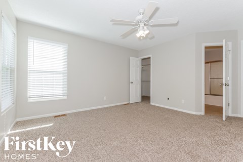 A spacious room with a ceiling fan and carpeted floor.