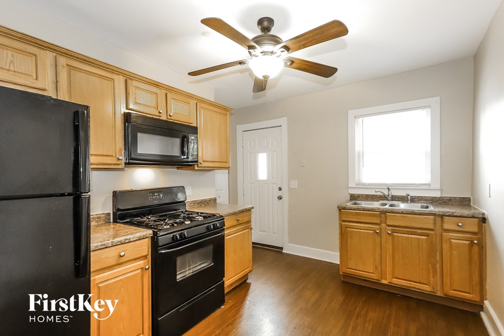 A kitchen with wooden cabinets and a black fridge.