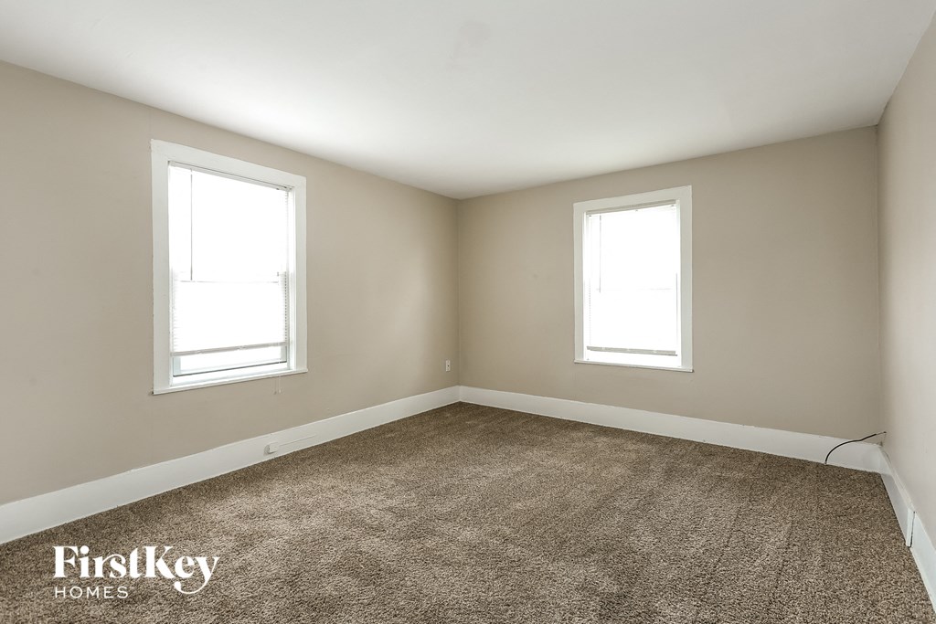 A room with two windows and a carpeted floor.