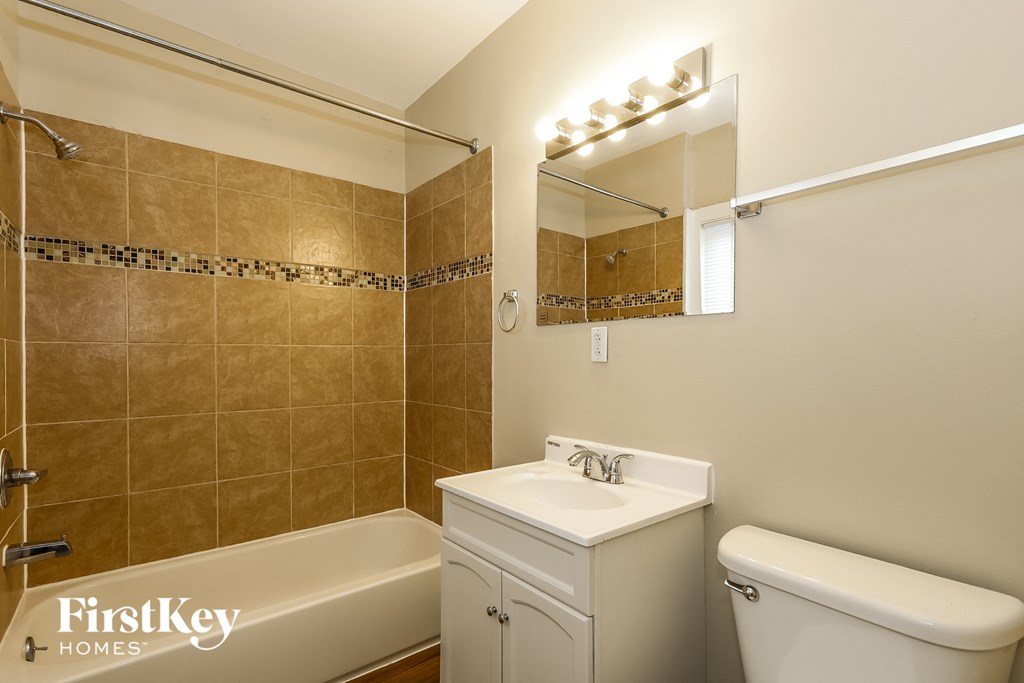 A bathroom with a beige tub, sink, and toilet.