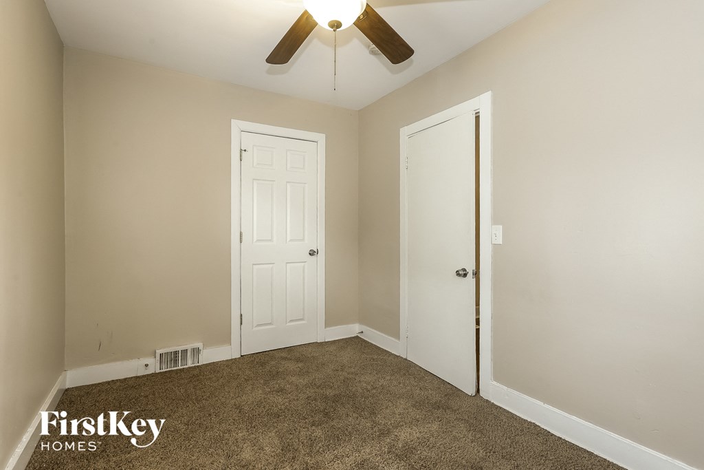 A room with a carpeted floor and two white doors.