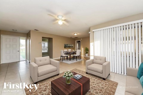 A living room with a brown coffee table and two white chairs.
