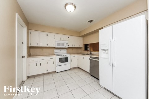 A kitchen with white appliances and cabinets.