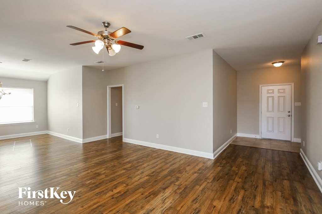 an empty living room with wood floors and a ceiling fan