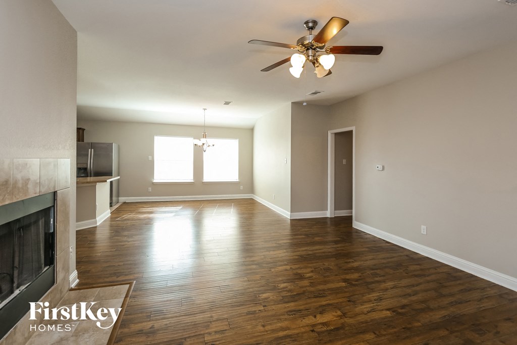 an empty living room with a ceiling fan and a fireplace