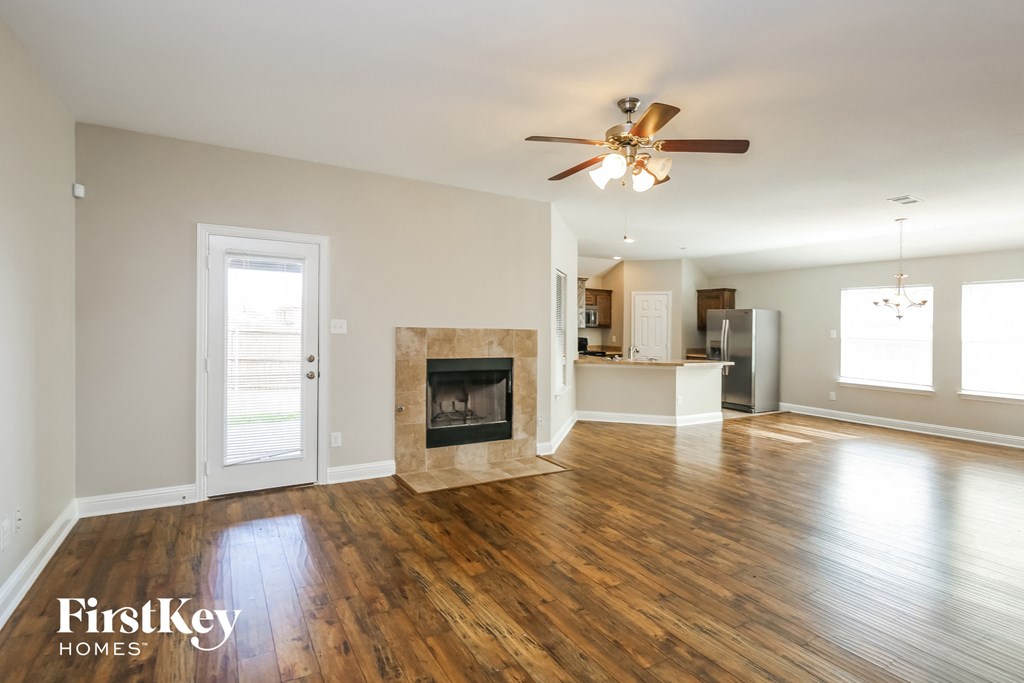 an empty living room with a fireplace and a ceiling fan