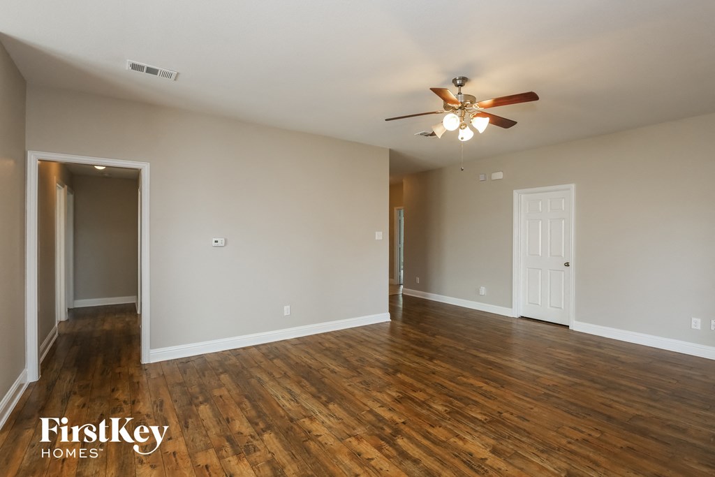 an empty living room with wooden floors and a ceiling fan