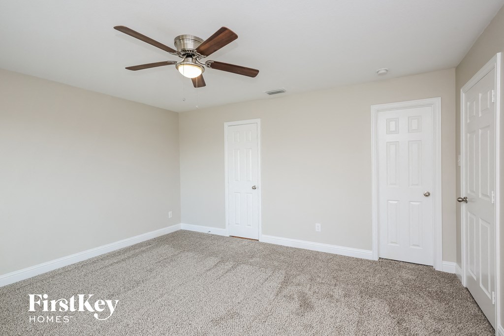 the living room of an empty home with a ceiling fan