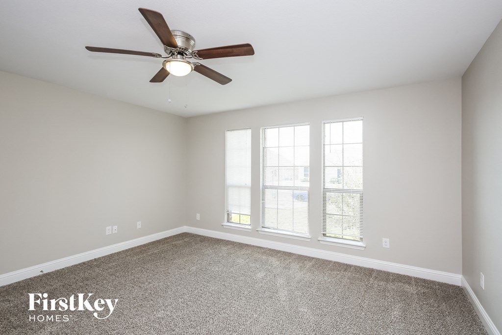 the spacious living room with ceiling fan and windows