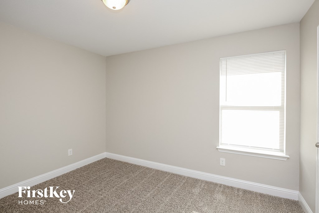 a bedroom with a window and a carpeted floor