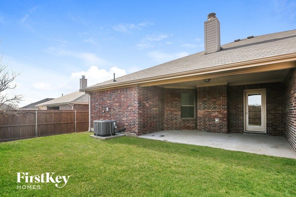 the backyard of a brick house with a patio and grass