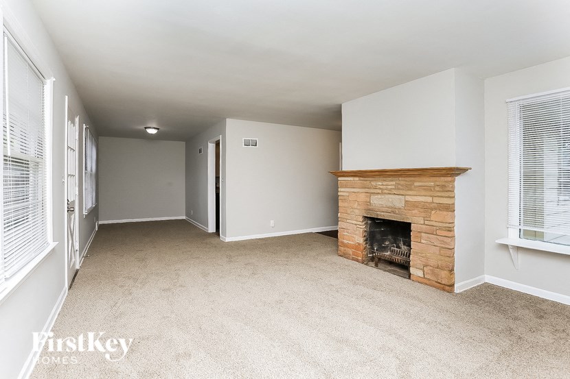 A living room with a fireplace and carpeted floor.