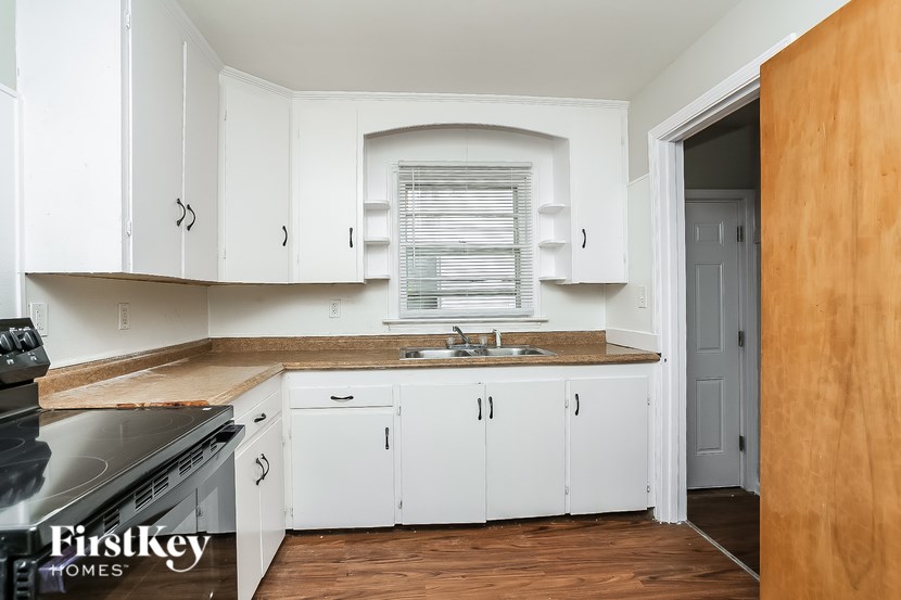 A kitchen with white cabinets and a wooden floor.