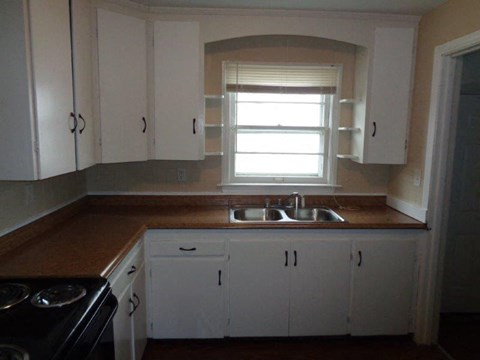 A kitchen with white cabinets and a black stove top oven.