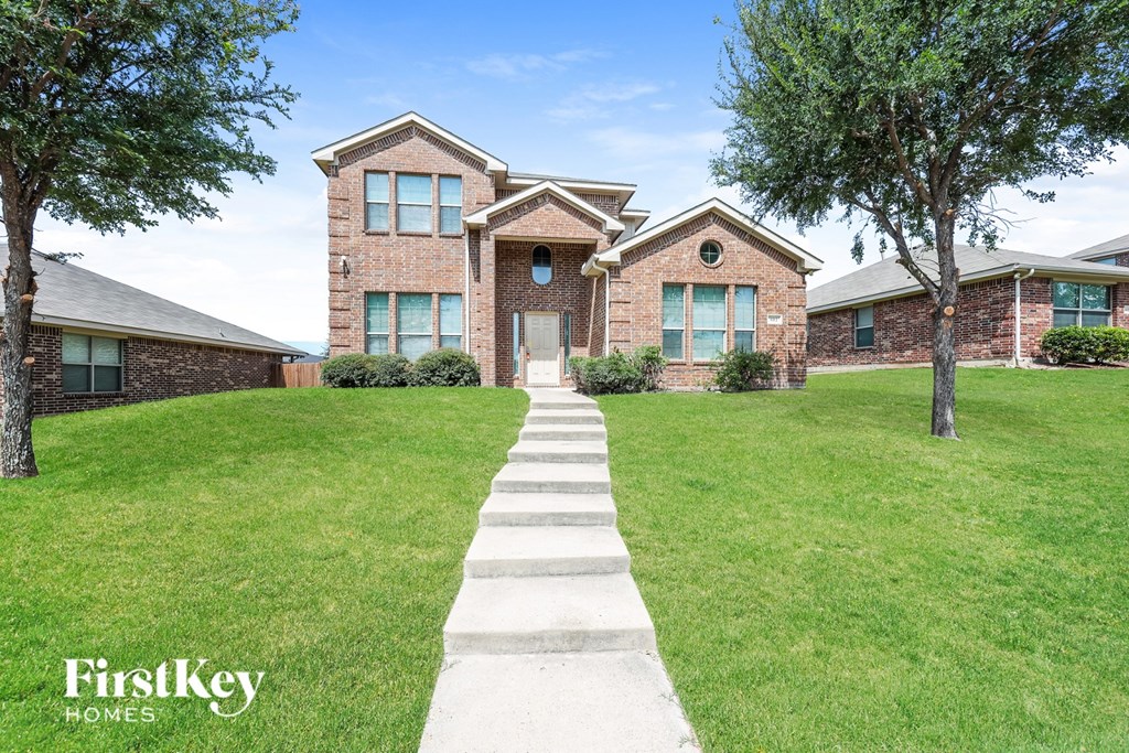 A brick house with a white walkway leading to the front door.