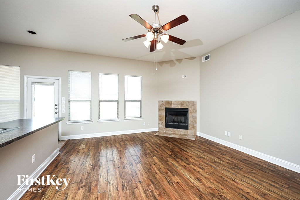 A spacious room with a fireplace and a ceiling fan.
