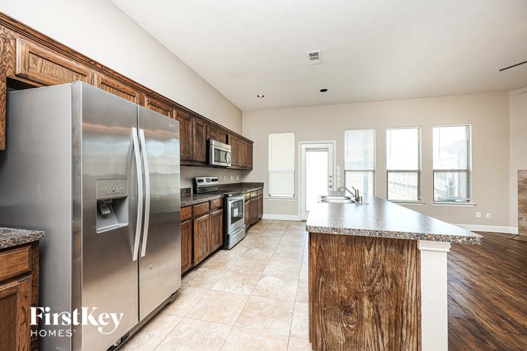 A kitchen with a stainless steel refrigerator and wooden cabinets.