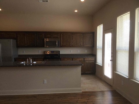 A kitchen with a black counter top and wooden cabinets.